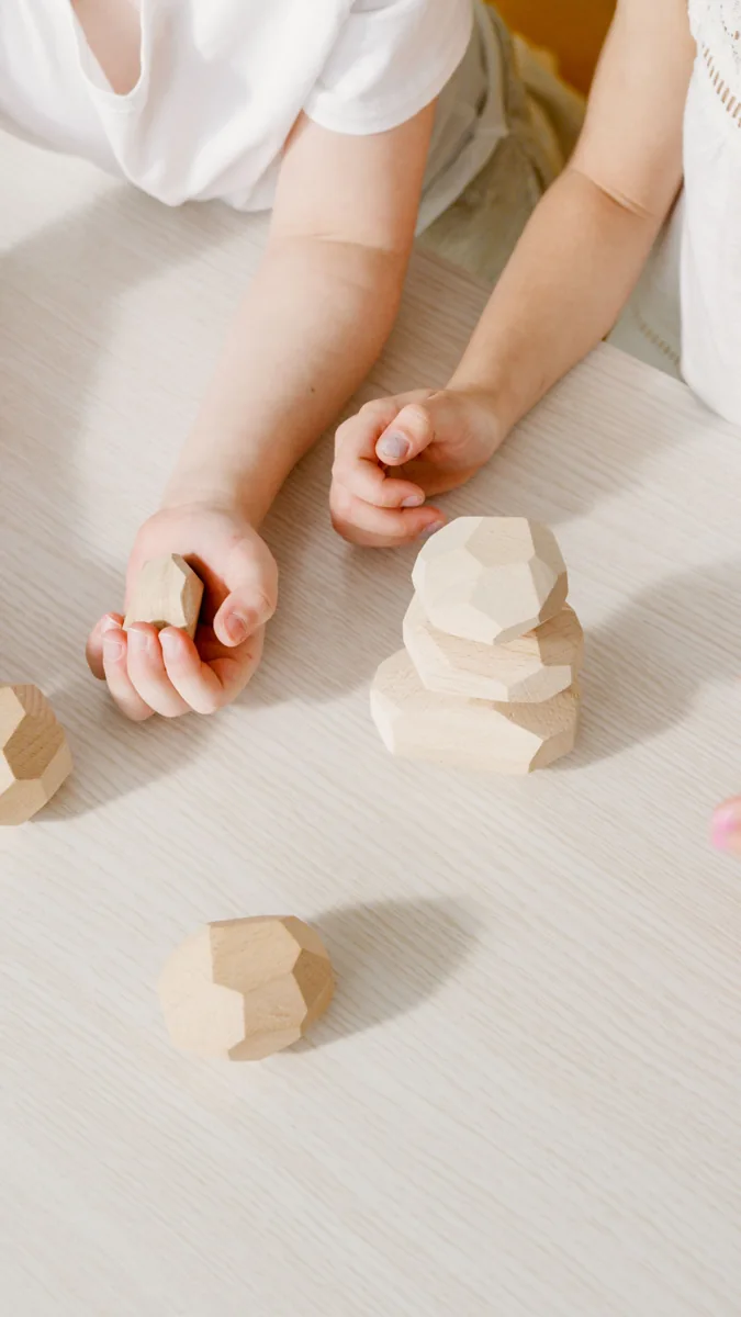 Hands arranging wooden building blocks